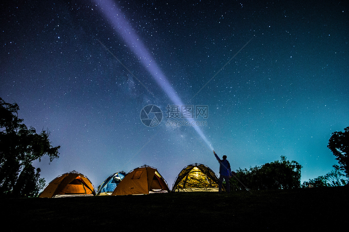 晚上露营。幸福的背包客夫妇坐在篝火和帐篷下，在难以置信的美丽星空下。村庄在山谷的背景。长时间曝光照片摄影图片_ID:158112008-Veer图库