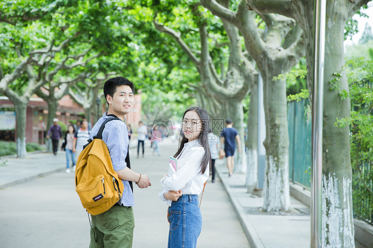 青春男女学生走在校园路上回头图片