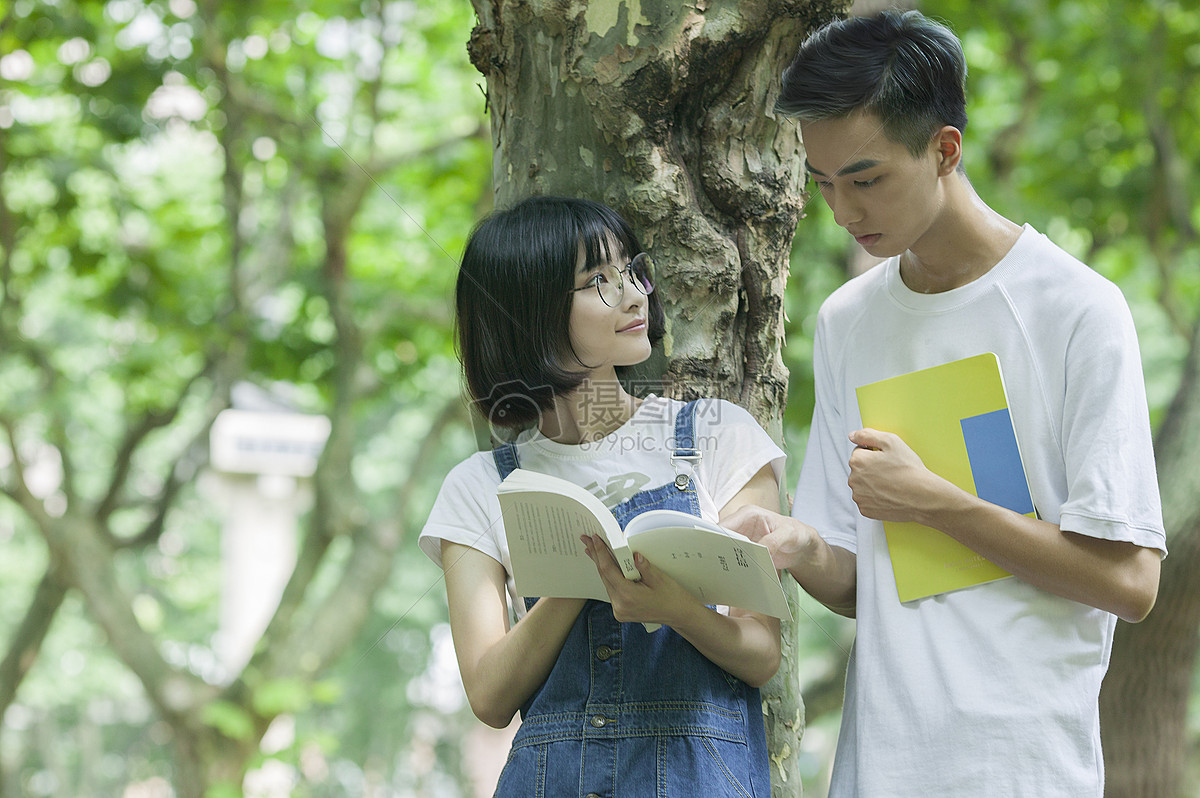 学校林荫道上男女同学下课一起学习看书