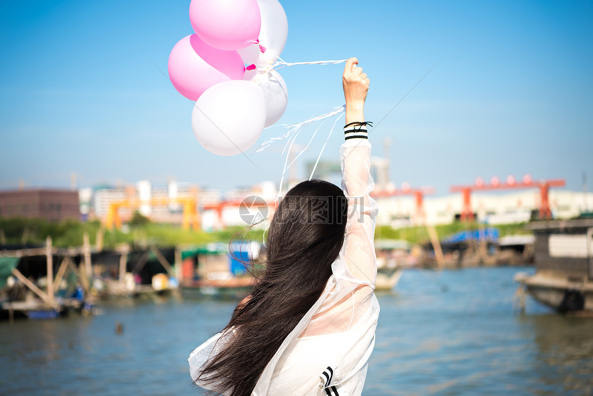 拿着气球的年轻女性背影