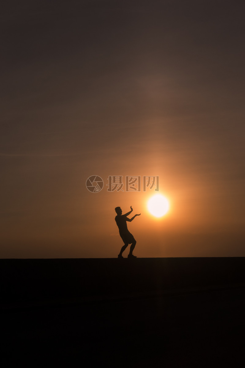 夕阳下男孩和太阳在做游戏