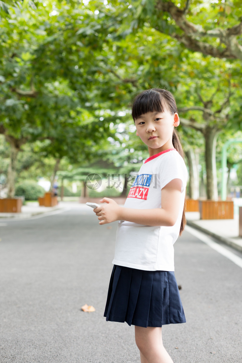 照片 教育文化 站在校园里玩手机的小学生女生.