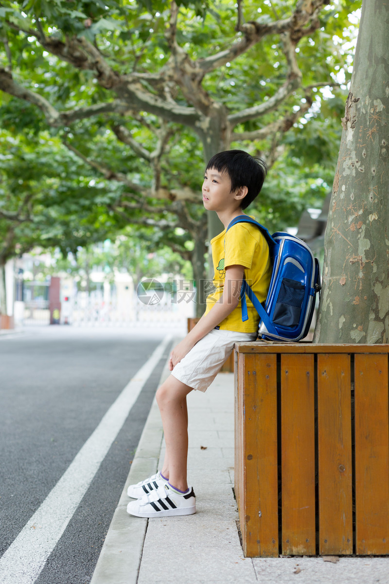 校园林荫道坐着等待家长的小学生