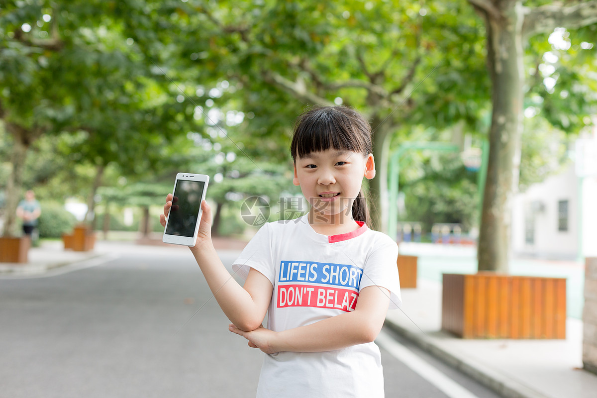 站在校园里玩手机的小学生女生