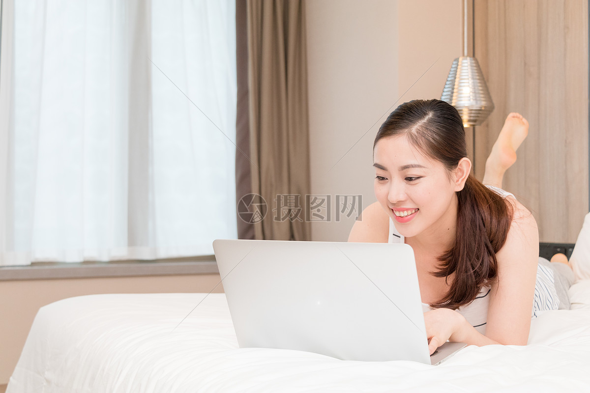 美女趴在床上玩电脑