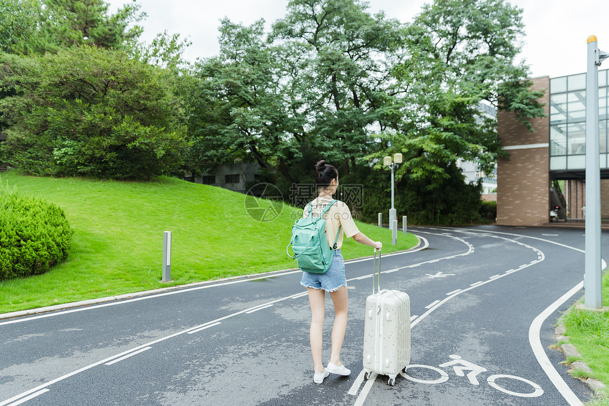 校园里拉着旅行箱的女生背影