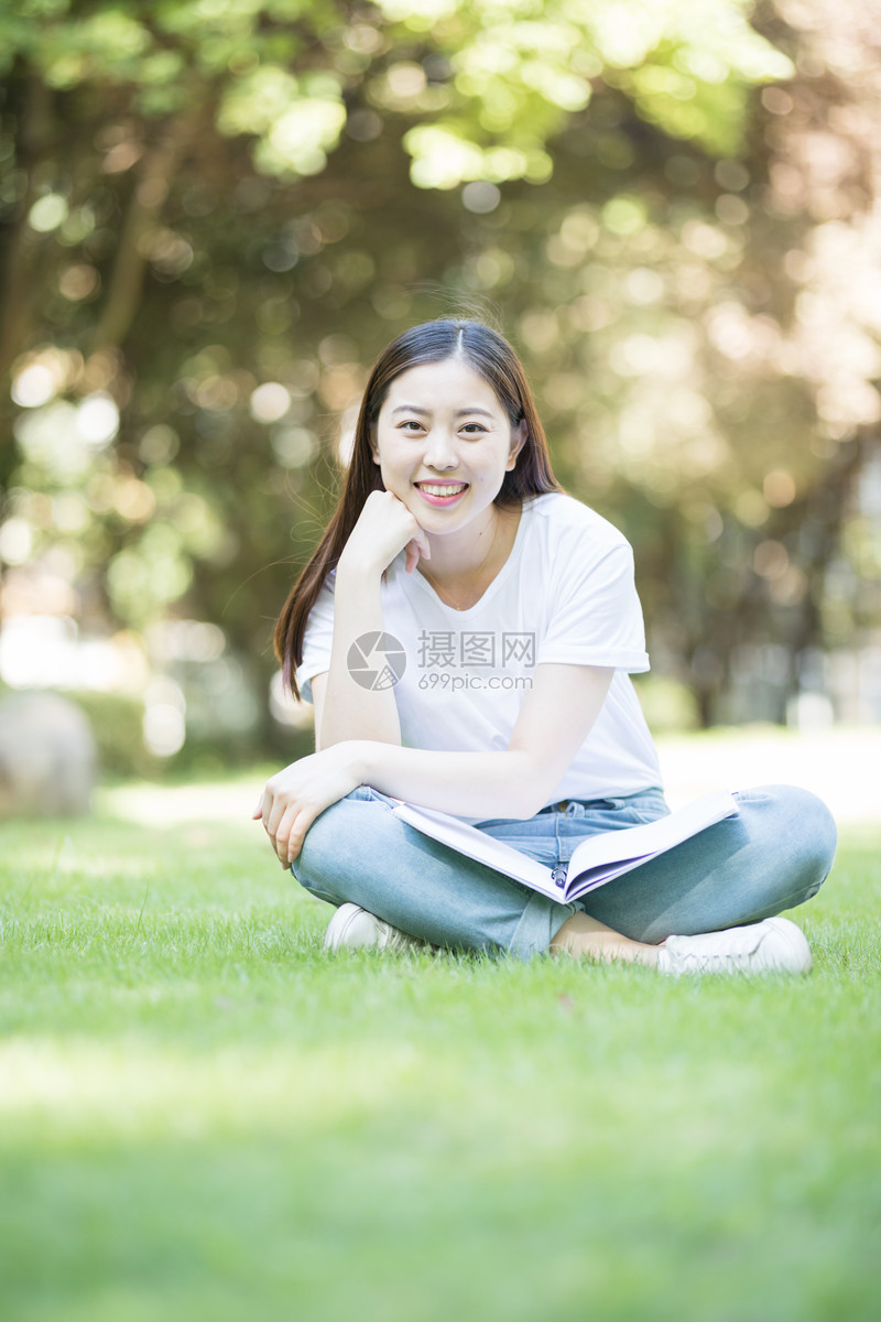 愉快地坐在草坪上学习的女同学