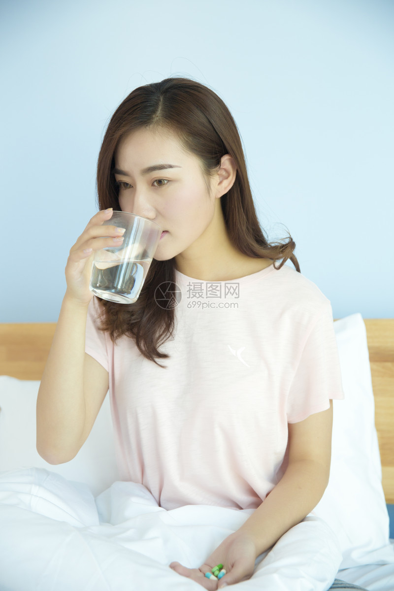 卧室里在床上吃药的女性
