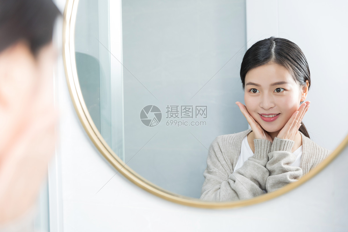 在家照镜子护肤美容的年轻女性