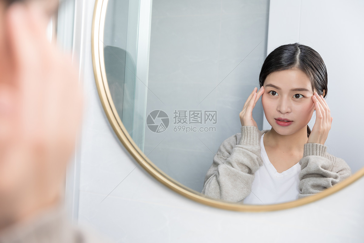 在家照镜子护肤美容的年轻女性