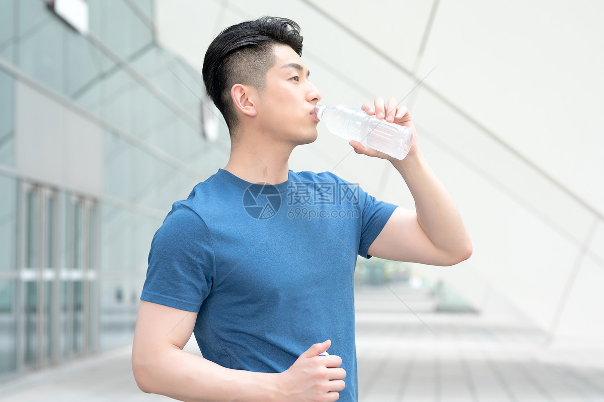 运动健身后站着喝水的年轻男性