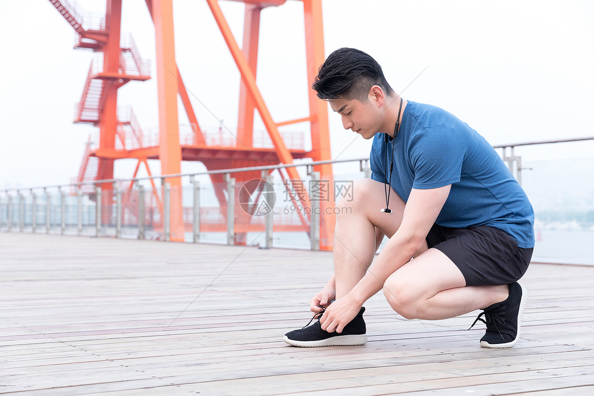 蹲着系鞋带的运动男性