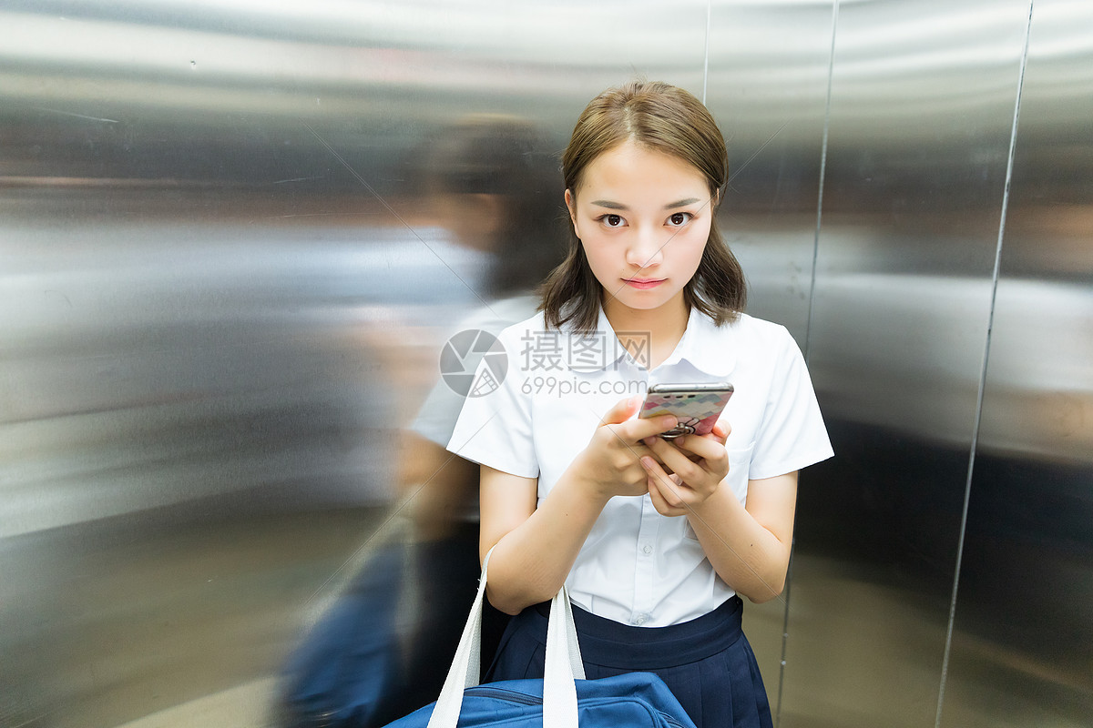 电梯内玩手机的女生