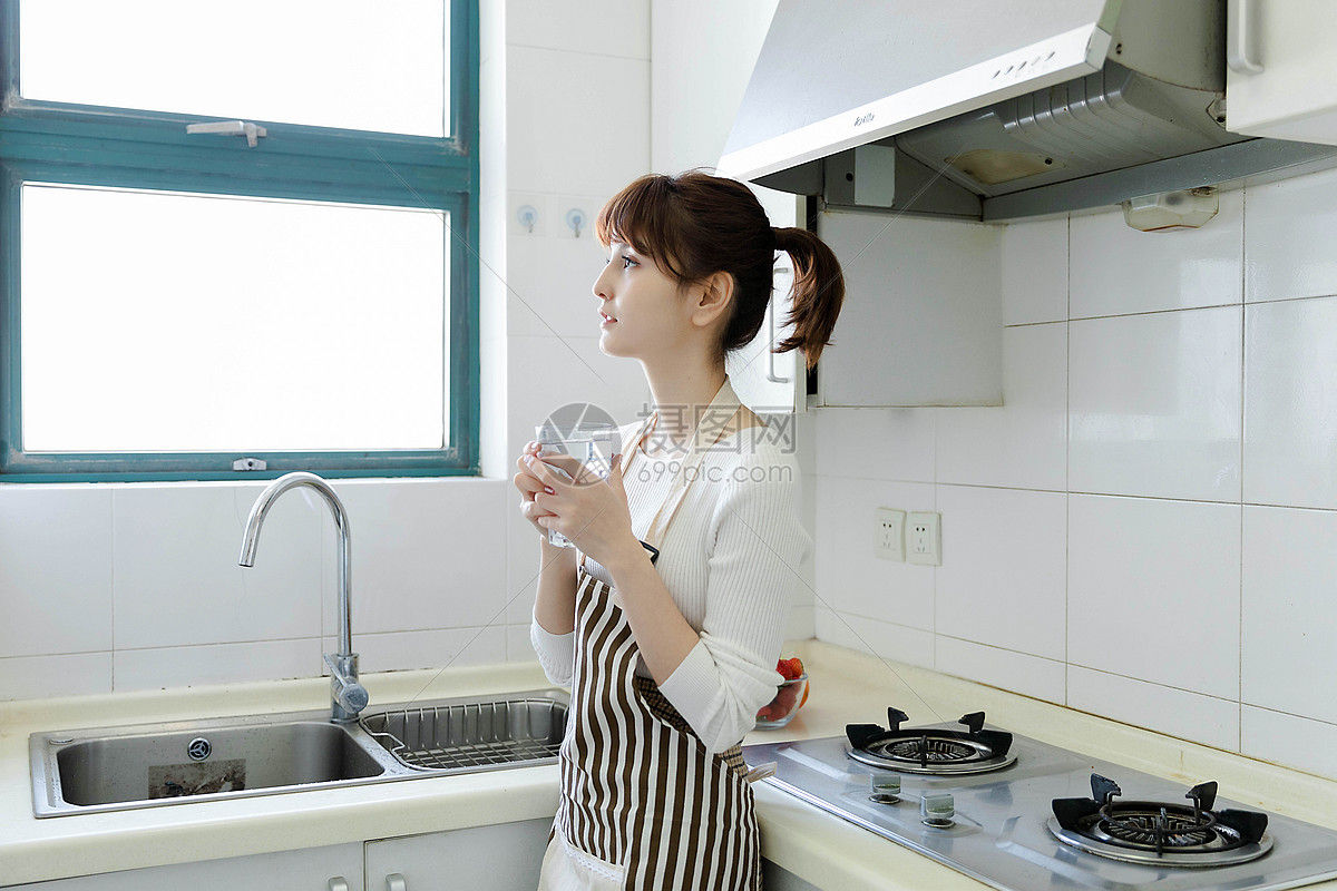 厨房里喝水的家庭主妇