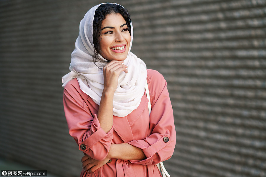 快乐的阿拉伯女人戴着头巾市中心散步城市背景中的穆斯林女性年轻的