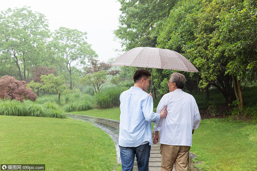 中老年父子下雨天撑伞逛公园背影亲人人物