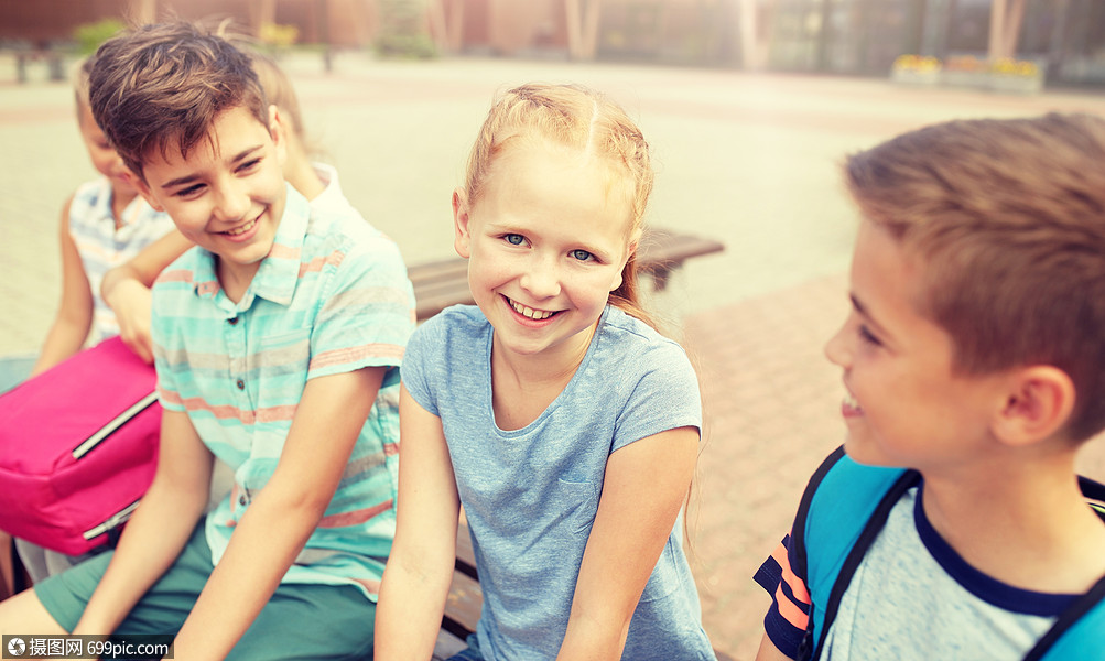 小学教育,友谊,童年,沟通人的群快乐的小学生,背包坐长凳上,户外交谈