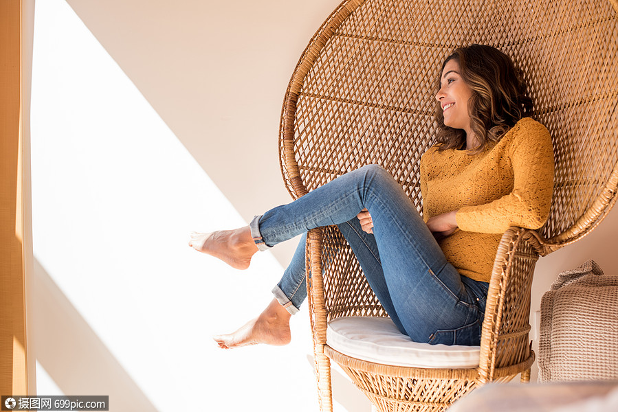 乐观的女人坐家里把舒适的藤椅上