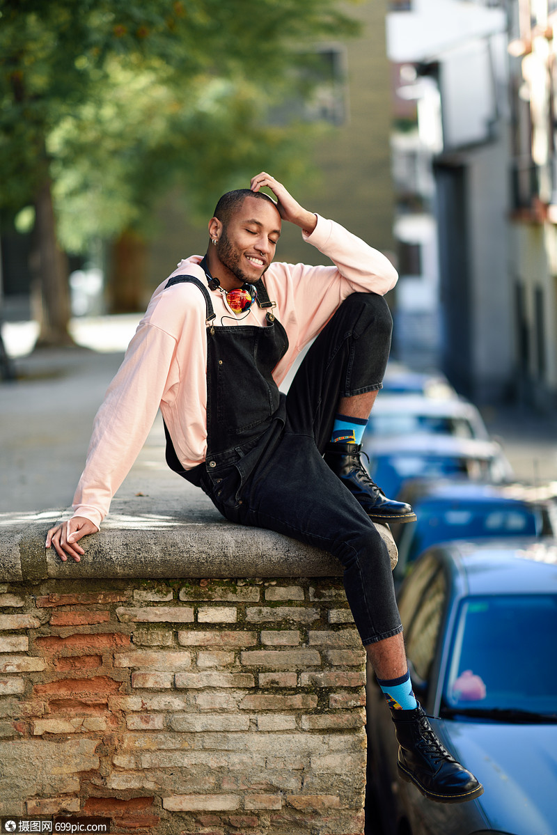 年轻的黑人穿着休闲服耳机坐城市背景上闭着眼睛享受快乐的非洲人带着