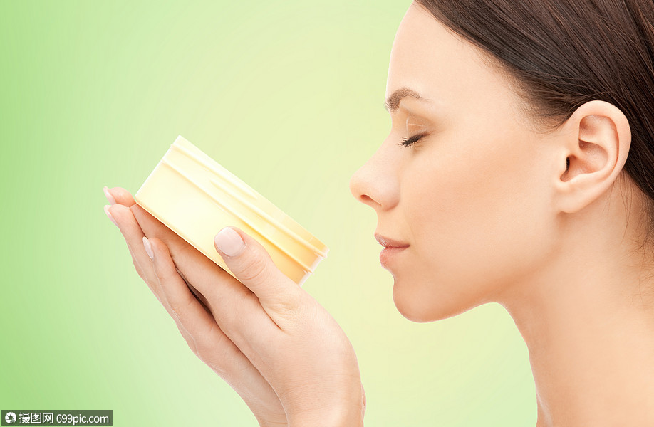 美丽,芳香化妆品的美丽的女人闻着滋润奶油的香气石灰绿色的自然背景