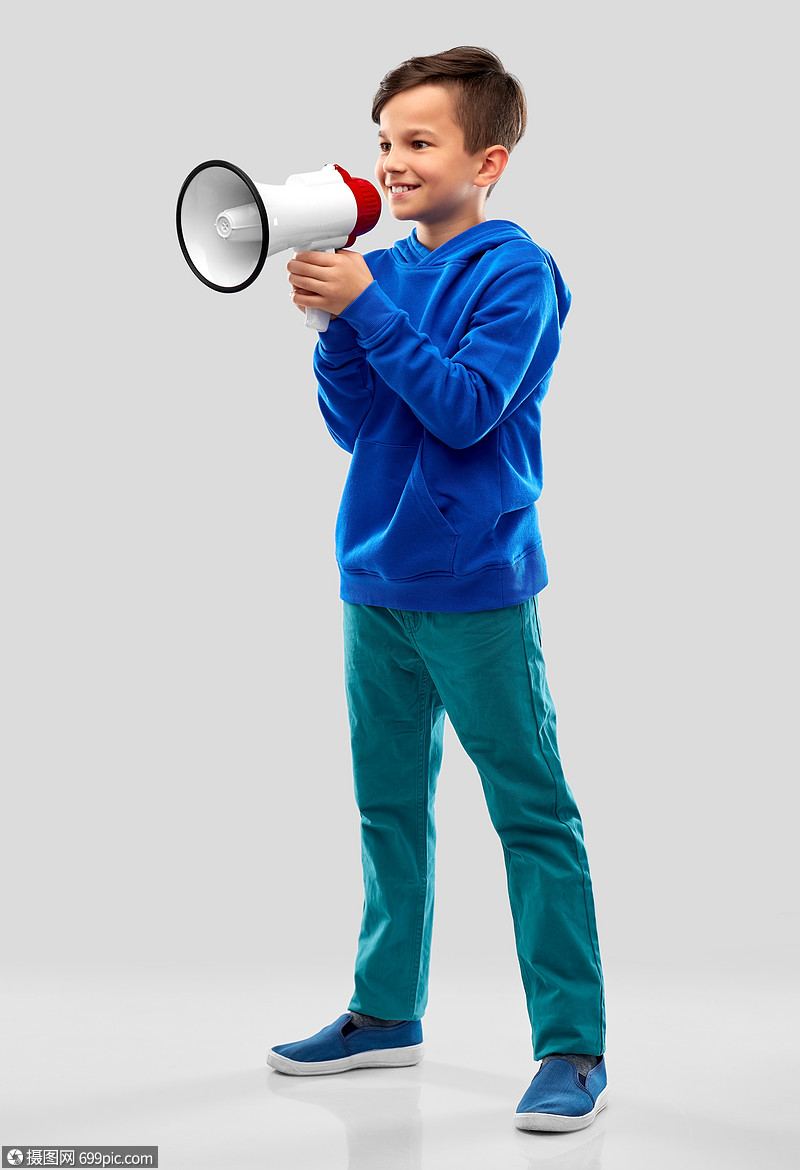 灰色背景下扩音器说话微笑的男孩扩音器说话