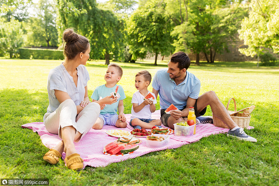 家庭休闲人的快乐的母亲,父亲两个小儿子夏天的公园野餐吃西瓜快乐的