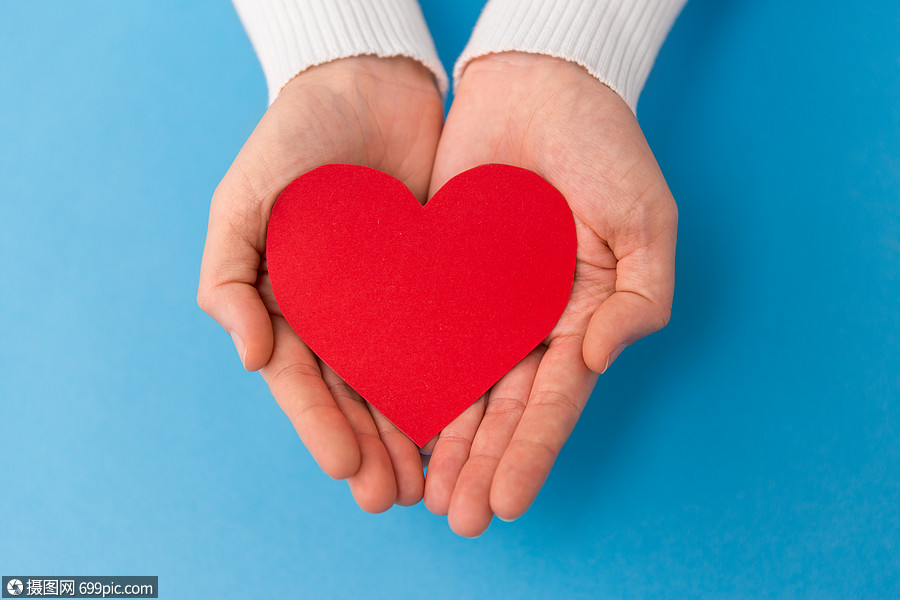 爱,健康情人节的手握红色心形蓝色背景双手握着蓝色背景上的红色心形
