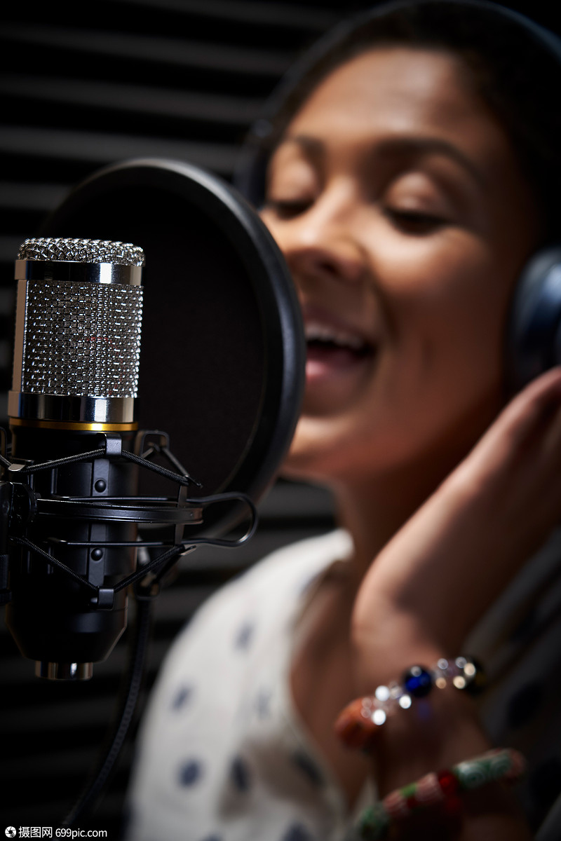 女歌手戴着耳机录音室着麦克风唱歌