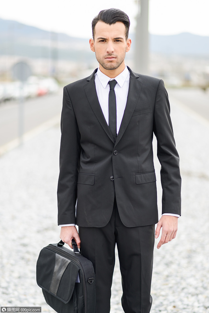 位轻商人办公楼附近的肖像,穿着黑色西装,系着现代发型