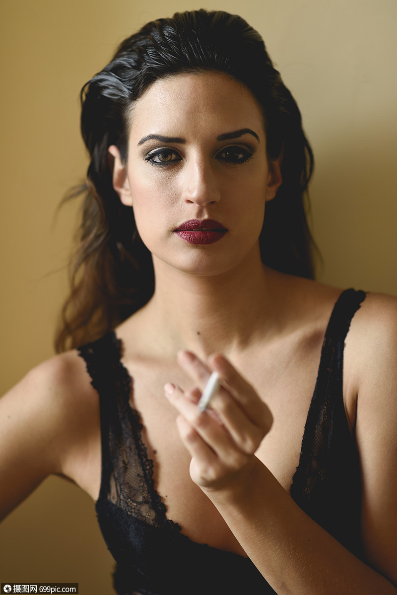 抽烟轻漂亮的黑发女人黄色背景上抽烟穿着黑色内衣的女孩吸烟美极了