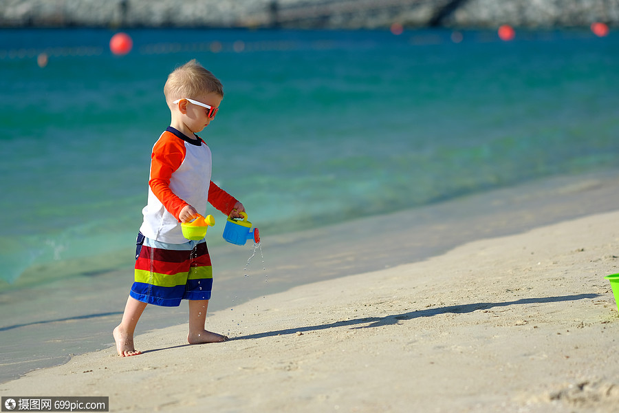 两岁的蹒跚学步的男孩海滩上玩海滩玩具