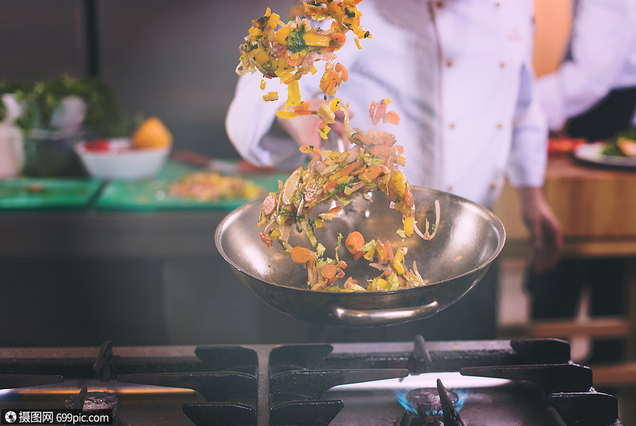 轻的男厨师商业厨房的炒菜厨师炒菜餐厅健康的