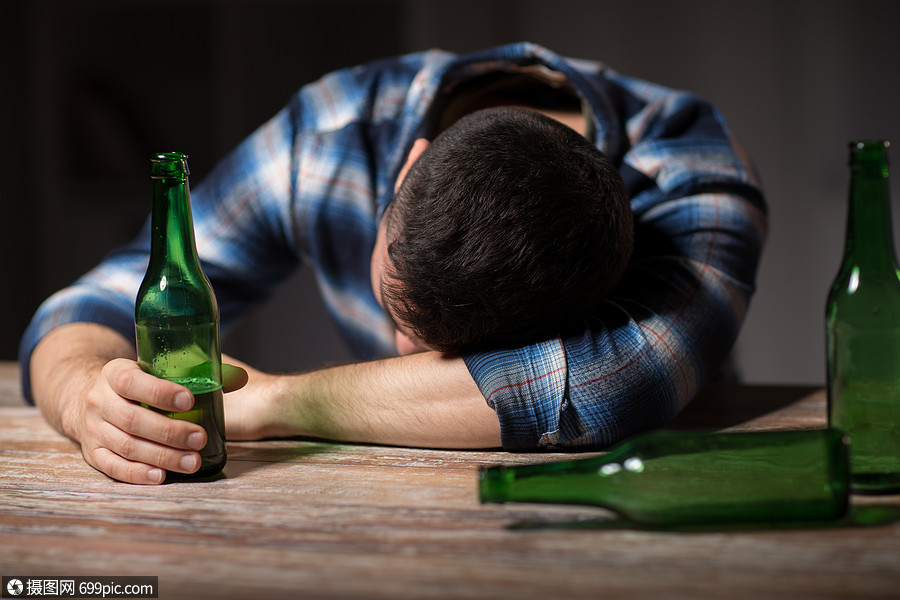 酒精成瘾人的男酒精与啤酒瓶躺桌子上晚上睡觉晚上桌