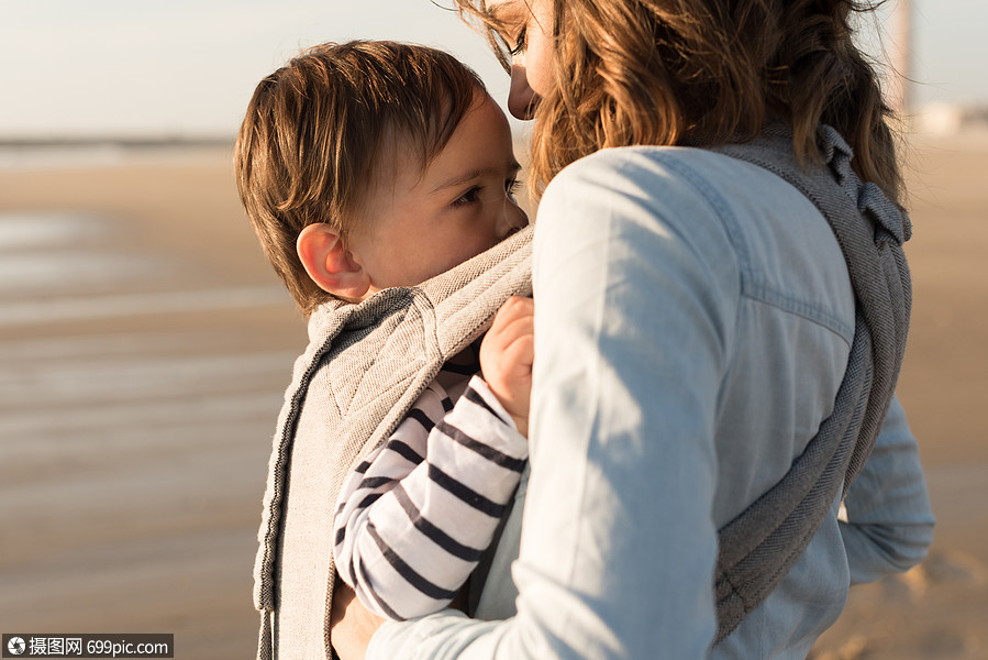 母亲带着麦格宝宝海滩上抱着蹒跚学步的孩子