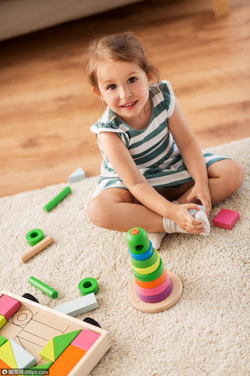 童人的快乐的三岁女婴玩玩具块家快乐的女婴家里玩玩具积木小的随便的