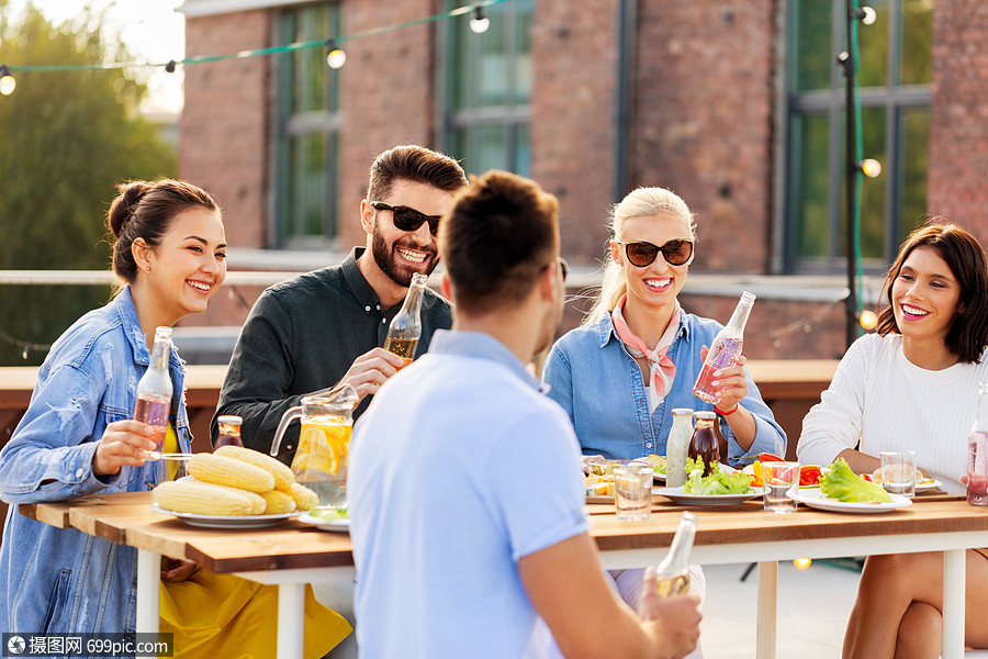 休闲人们的快乐的朋友与饮料屋顶聚会快乐的朋友屋顶饮料的快乐朋友