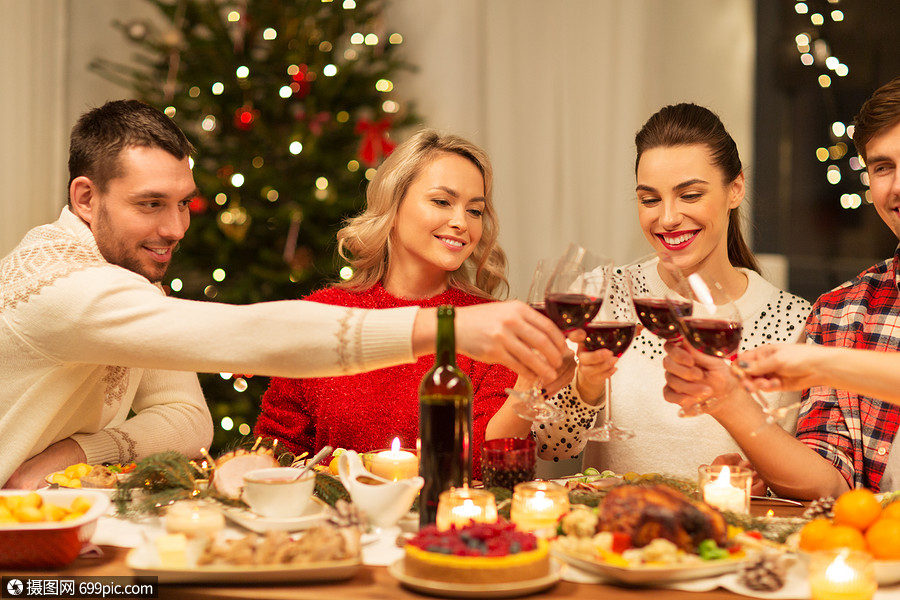 节日庆祝快乐的朋友家里吃诞晚餐,喝红酒碰杯快乐的朋友诞节聚会上喝