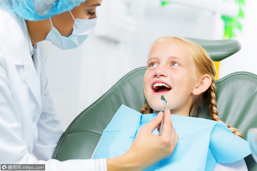 牙齿检查可爱的微笑女孩坐扶手椅上看牙医