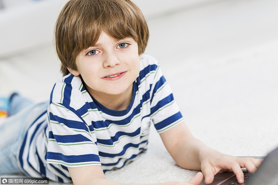 可爱的男孩躺地板上用笔记本电脑玩电脑游戏