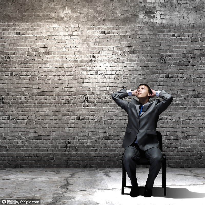 失业轻的商人坐椅子上,膝盖上放着手提箱