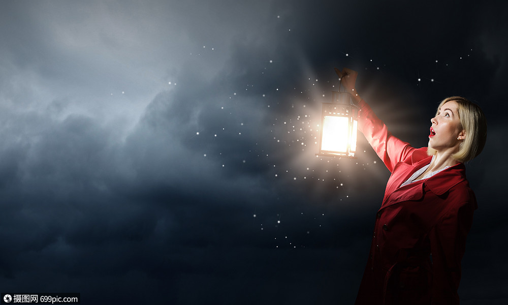 迷失的女人轻的金发女郎穿着红色斗篷,黑暗中着灯笼光树