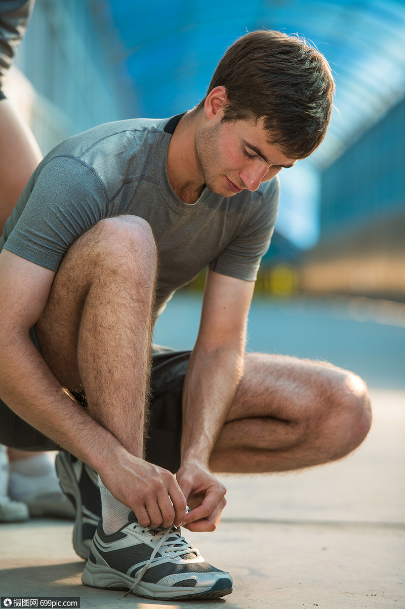 英俊的男人户外跑步前系鞋带运动装之前