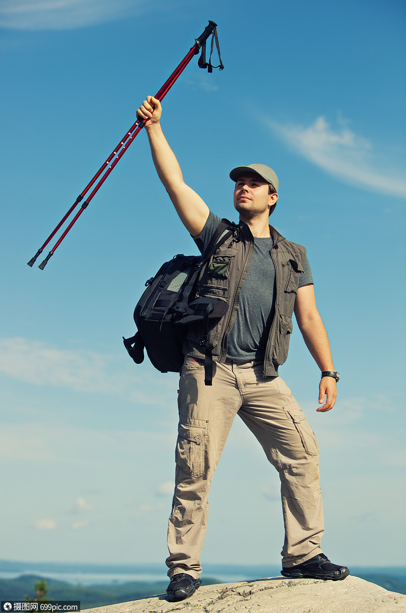 轻人游客,背包站山顶,着棍子头顶上