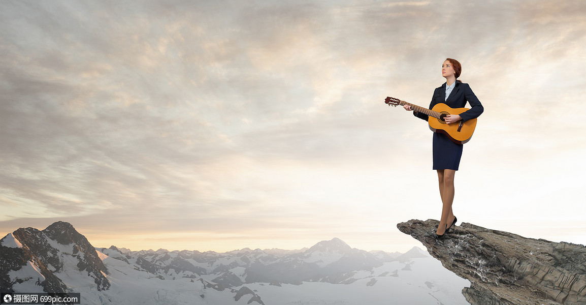 女商人弹声吉他开朗的女商人站岩石边缘弹吉他成功的站立