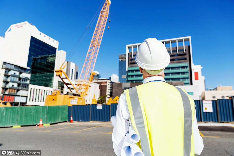 建築工地的工程師建設者工程師建築工人施工場景穿著帶藍圖的安全背心