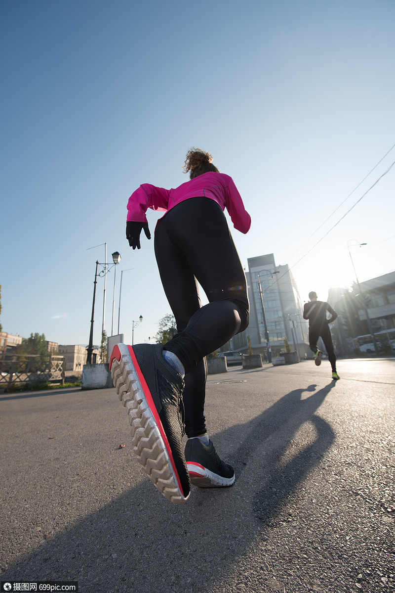 健康的轻夫妇清晨城市慢跑,背景日出