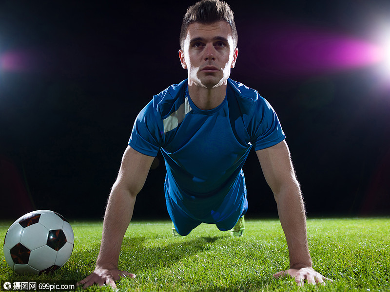 足球运动员足球场上踢球,黑色背景上被隔离