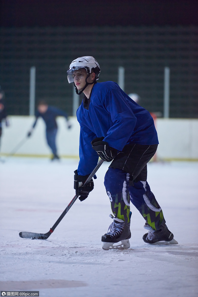 冰球运动员动作中用棍子踢健康的英俊的