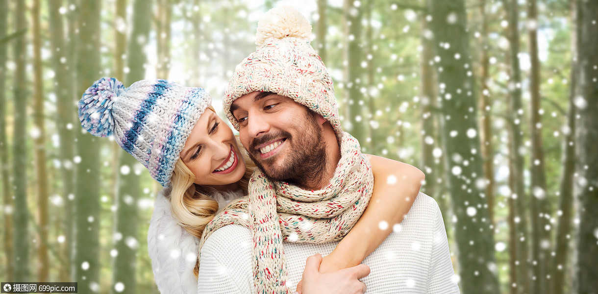 冬天,时尚,情侣,诞节人的微笑的男人女人戴着帽子围巾拥抱雪花森林