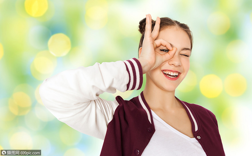 岁的女孩脸,并绿色的暑假灯光背景下玩得开心快乐的十几岁的女孩鬼脸